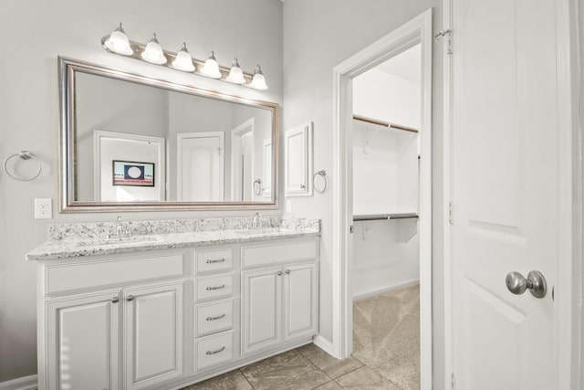 bathroom featuring a spacious closet, a sink, tile patterned flooring, and double vanity