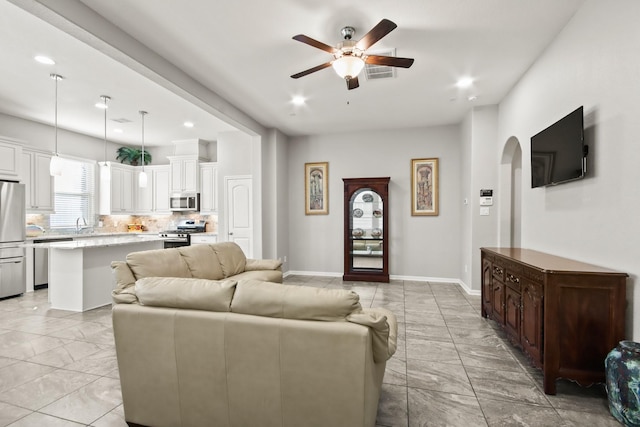 living area with marble finish floor, arched walkways, visible vents, and a ceiling fan