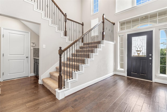 foyer with stairs, baseboards, a high ceiling, and dark wood-style flooring