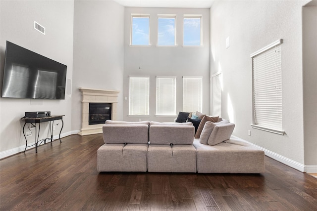 living area featuring a glass covered fireplace, visible vents, baseboards, and wood finished floors