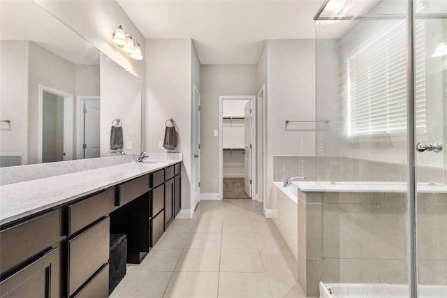 bathroom with tile patterned flooring, a spacious closet, baseboards, a bath, and vanity