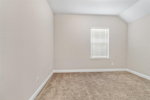 empty room featuring baseboards, lofted ceiling, and carpet flooring