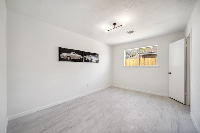 empty room with visible vents, baseboards, a textured ceiling, and marble finish floor