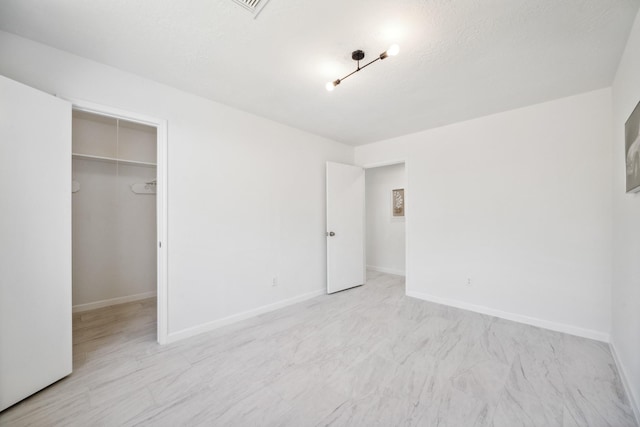 unfurnished bedroom with a closet, a walk in closet, and baseboards