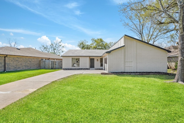 mid-century home featuring brick siding, board and batten siding, a front lawn, and fence