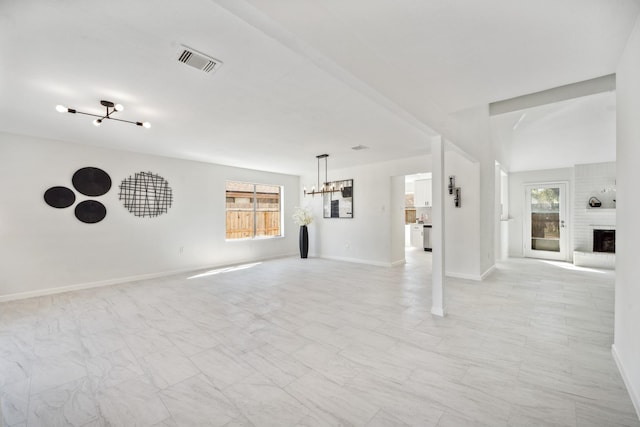 unfurnished living room with visible vents, baseboards, and a chandelier