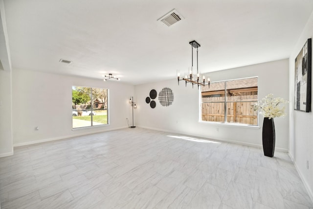 empty room with visible vents, baseboards, and an inviting chandelier