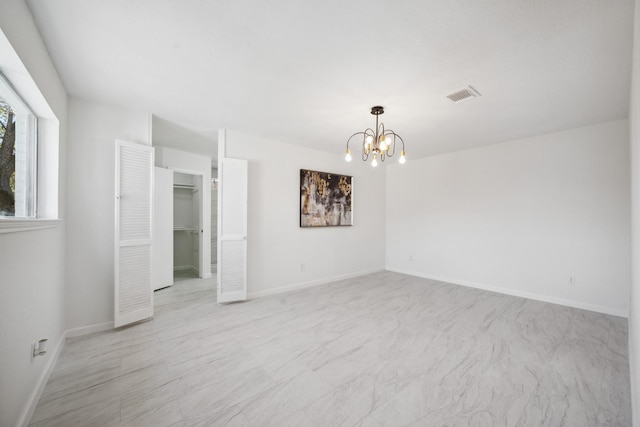 empty room featuring a notable chandelier, visible vents, and baseboards