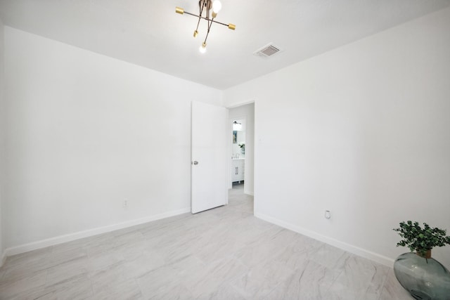 unfurnished room with visible vents, baseboards, and a notable chandelier