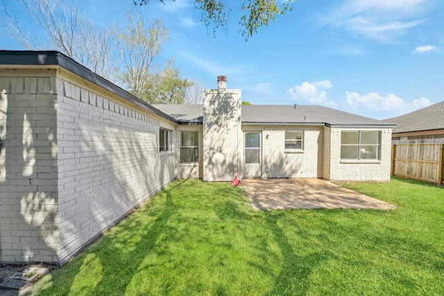 back of house featuring brick siding, fence, a chimney, a yard, and a patio area