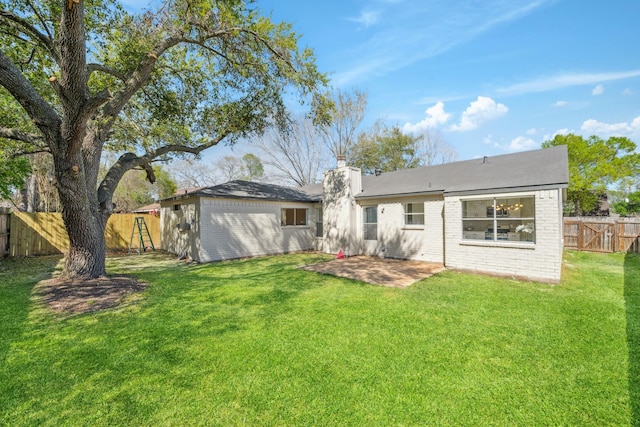 rear view of house with brick siding, a yard, a patio, and a fenced backyard