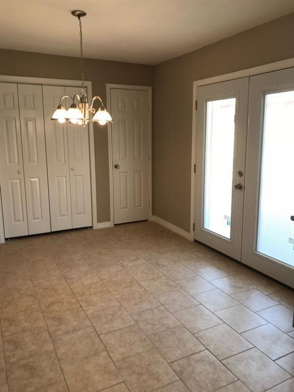 unfurnished dining area with a chandelier, french doors, and baseboards