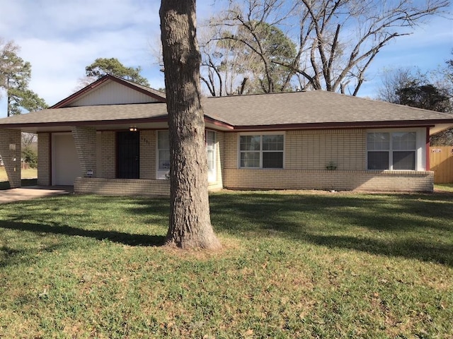 single story home featuring a front yard, an attached garage, brick siding, and roof with shingles