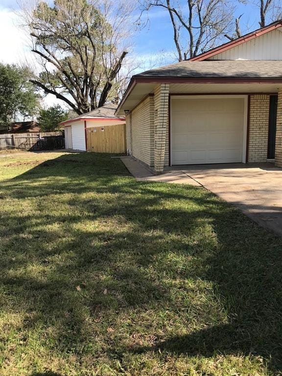 garage with concrete driveway and fence