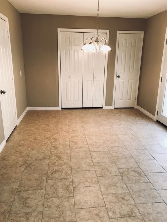 unfurnished dining area with a chandelier, light tile patterned floors, and baseboards