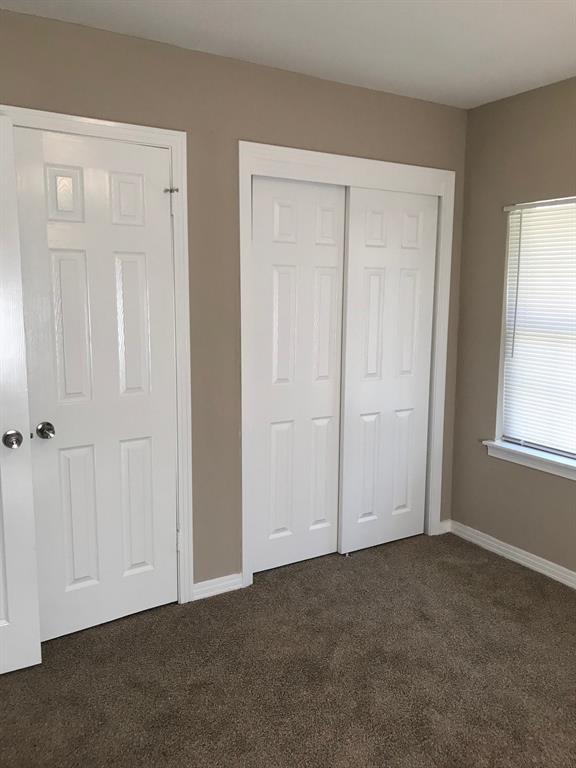 unfurnished bedroom featuring baseboards, dark colored carpet, and a closet