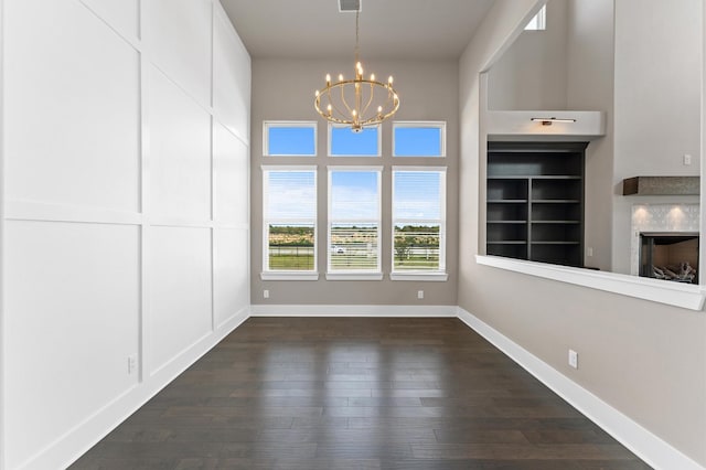 interior space with baseboards, a fireplace, an inviting chandelier, and dark wood finished floors