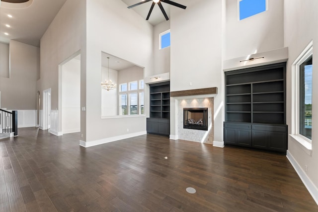 unfurnished living room featuring baseboards, dark wood-type flooring, and a healthy amount of sunlight