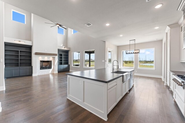 kitchen with a sink, dark countertops, dark wood-style floors, visible vents, and ceiling fan