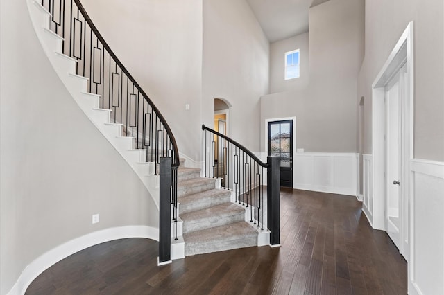 foyer entrance with wainscoting, a towering ceiling, stairway, and wood-type flooring