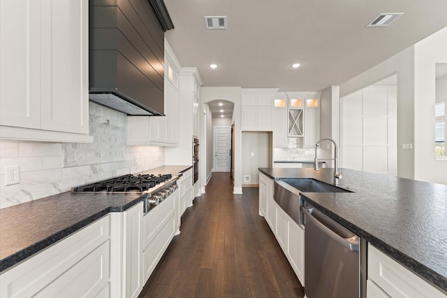 kitchen with dark countertops, stainless steel appliances, arched walkways, and visible vents