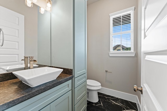 bathroom featuring marble finish floor, baseboards, toilet, and vanity