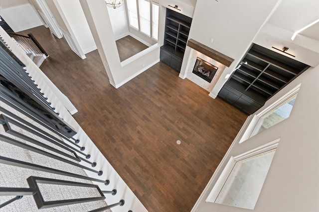stairway featuring baseboards, a fireplace, and wood finished floors