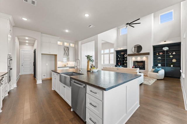 27003 Skiers Crossing Dr, Katy, TX 77493 - kitchen with dishwasher, dark countertops, arched walkways, white cabinetry, and dark wood-style flooring