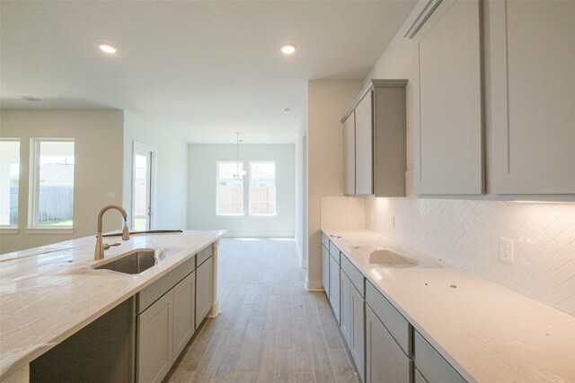 kitchen with a sink, light wood-type flooring, recessed lighting, gray cabinets, and backsplash