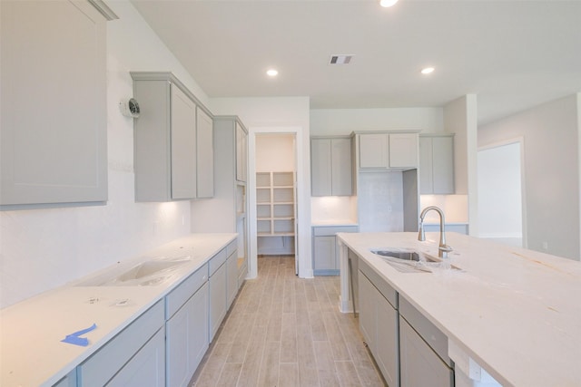 kitchen featuring light wood-type flooring, visible vents, light countertops, and a sink
