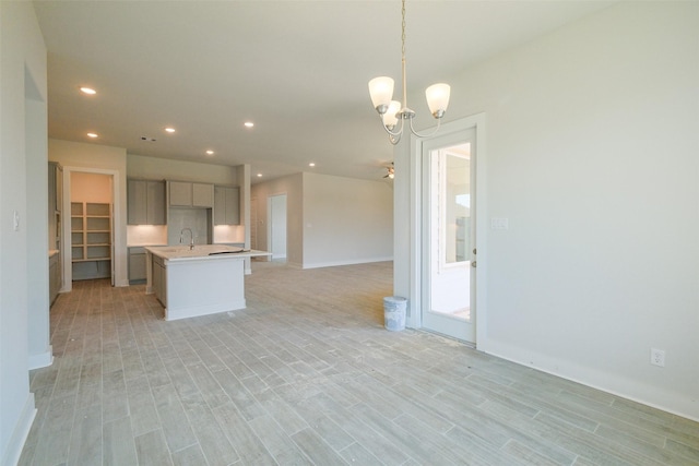 kitchen featuring an island with sink, an inviting chandelier, recessed lighting, light countertops, and open floor plan