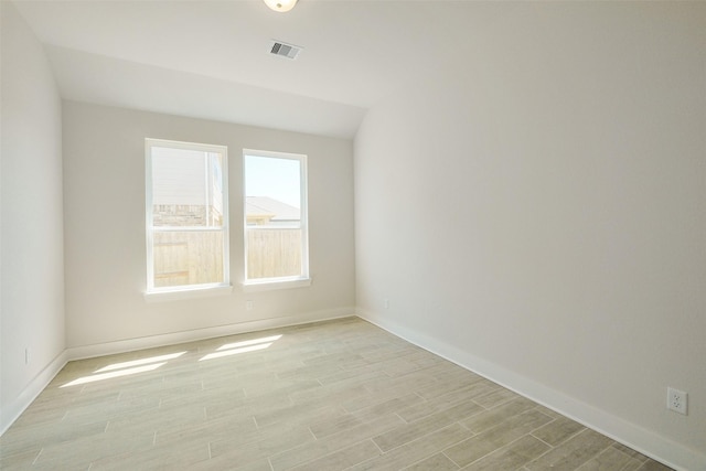 spare room with light wood finished floors, visible vents, and baseboards