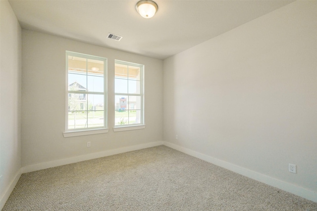 carpeted spare room featuring visible vents and baseboards