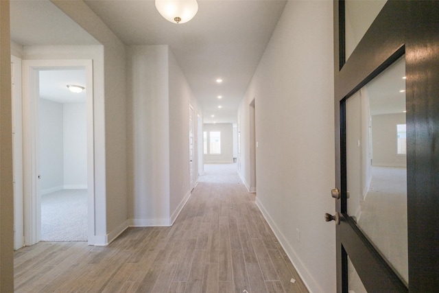 corridor featuring recessed lighting, light wood-type flooring, and baseboards