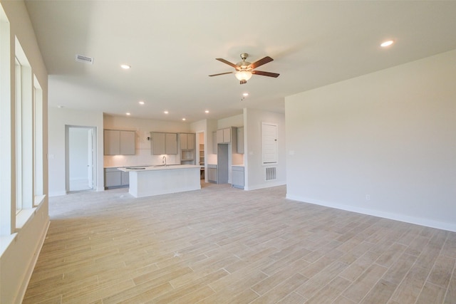 unfurnished living room featuring light wood-type flooring, a ceiling fan, visible vents, recessed lighting, and baseboards