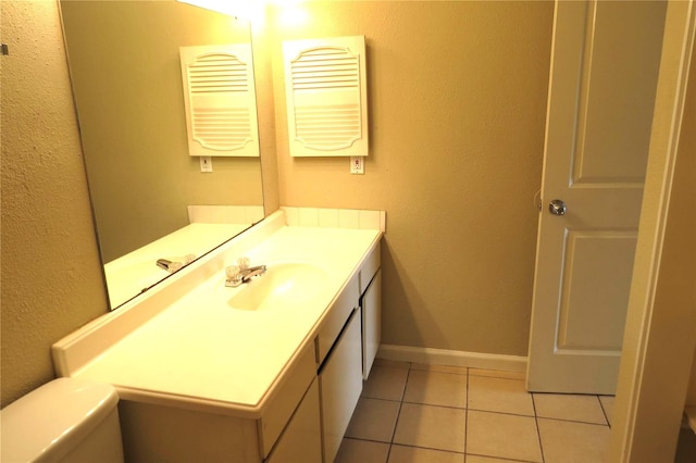 bathroom featuring baseboards, toilet, a textured wall, tile patterned floors, and vanity