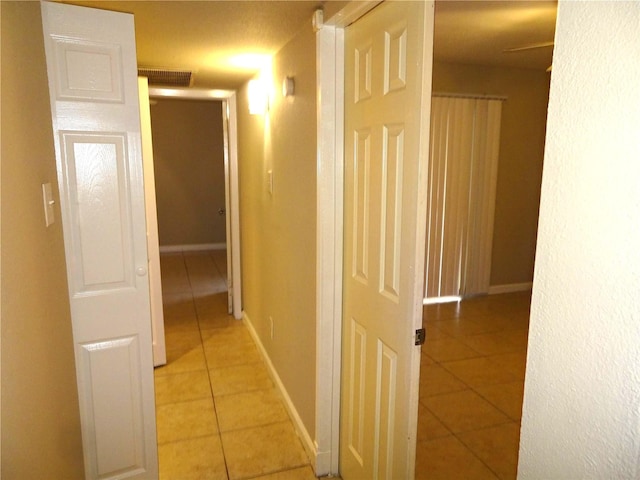 corridor with light tile patterned floors and baseboards