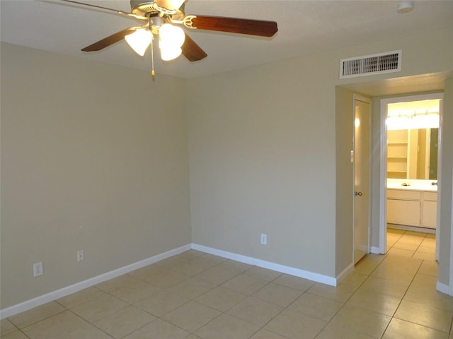 spare room featuring light tile patterned floors, a ceiling fan, visible vents, and baseboards