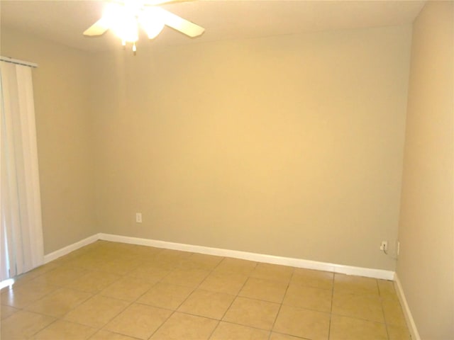 empty room with light tile patterned flooring, baseboards, and a ceiling fan