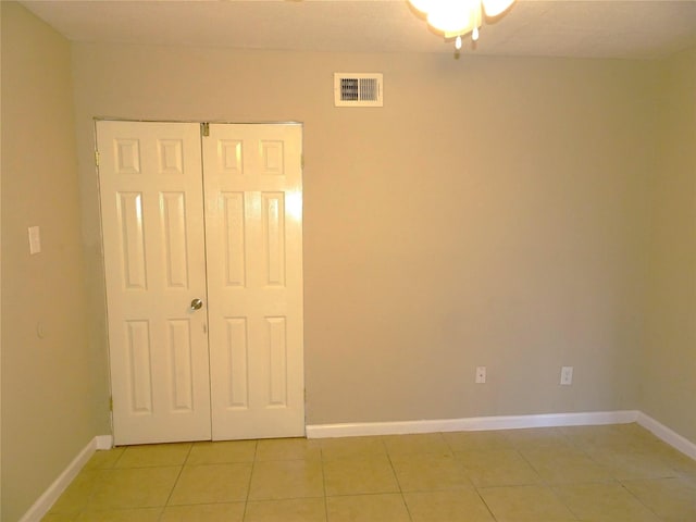 unfurnished bedroom featuring light tile patterned floors, visible vents, a closet, and baseboards