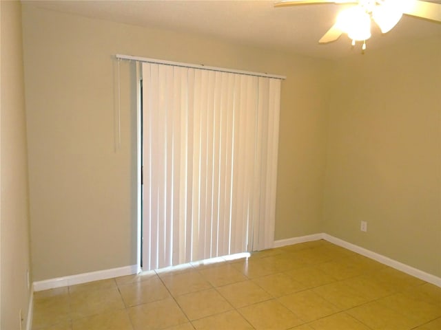 spare room featuring light tile patterned floors, a ceiling fan, and baseboards