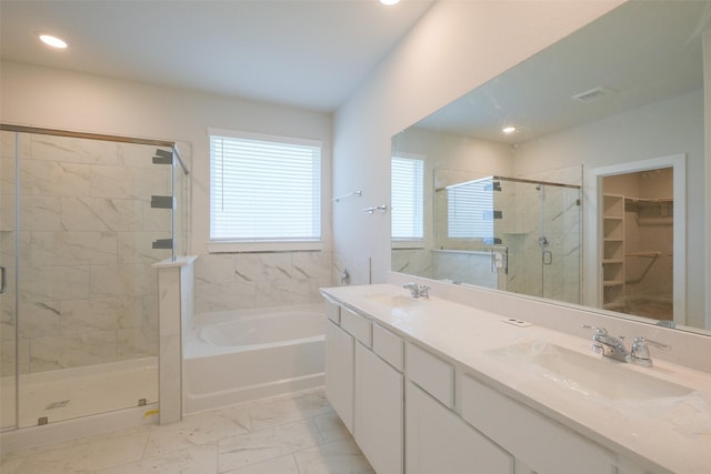 bathroom featuring a stall shower, a garden tub, marble finish floor, and a sink