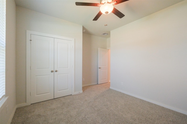 unfurnished bedroom with a closet, baseboards, light carpet, a ceiling fan, and visible vents