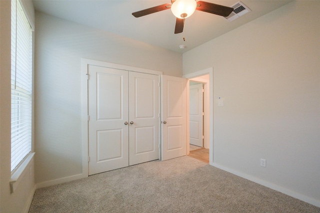 unfurnished bedroom featuring a closet, visible vents, light colored carpet, and baseboards