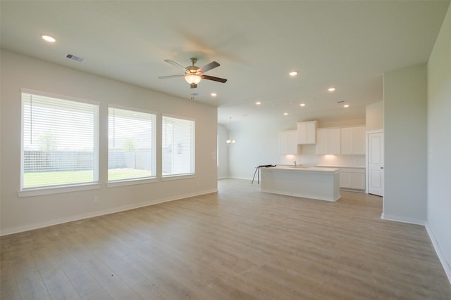 unfurnished living room featuring light wood finished floors, ceiling fan, visible vents, and recessed lighting