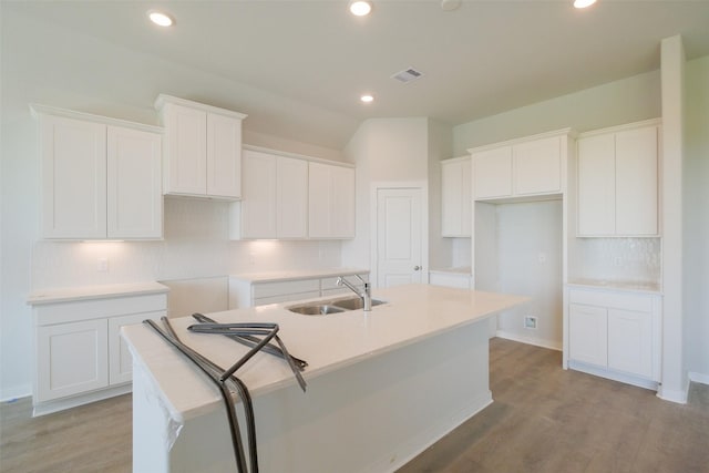 kitchen featuring light wood-style floors, an island with sink, a sink, and white cabinetry