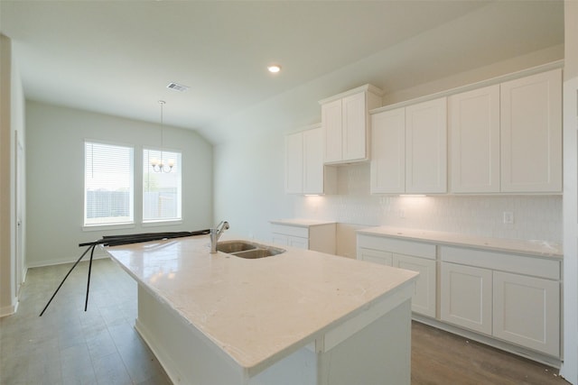 kitchen with an inviting chandelier, white cabinets, a kitchen island with sink, visible vents, and a sink