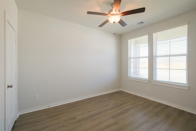 empty room featuring dark wood-type flooring, baseboards, a ceiling fan, and visible vents