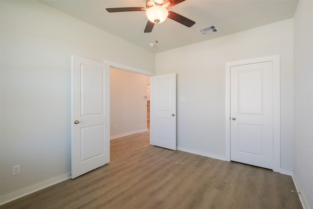 unfurnished bedroom with wood finished floors, ceiling fan, baseboards, and visible vents