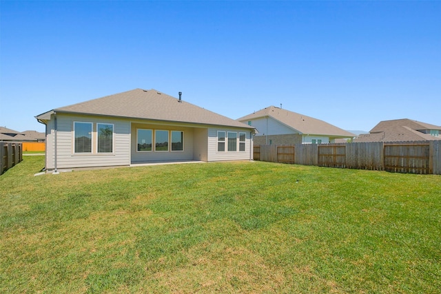 rear view of property featuring a yard and a fenced backyard